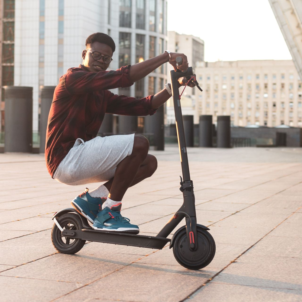 E-Scooter mit beeindruckender Reichweite Mann fährt auf E-Scooter in der Hocke