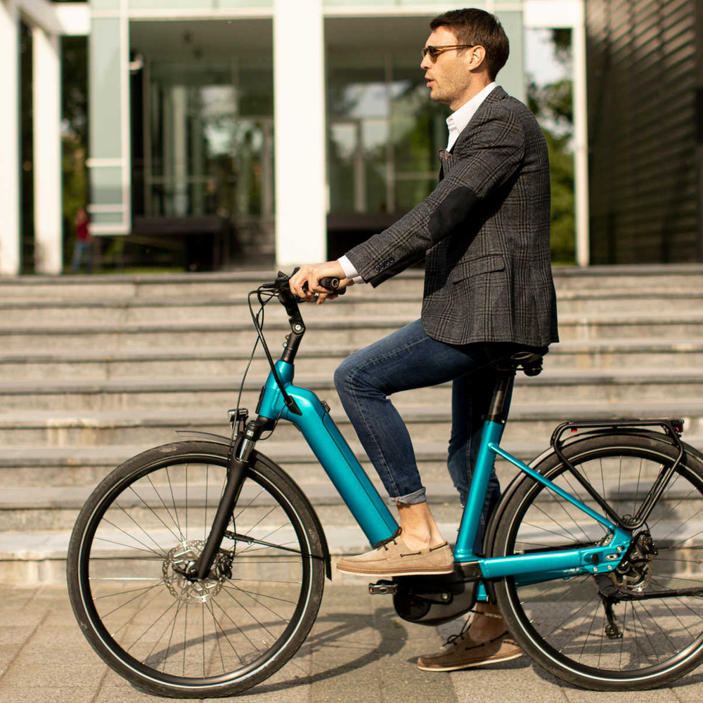 Tenways E-Bikes: Die Fahrradmarke für umweltbewusste Pendler. Junger Geschäftsmann sitzt auf E-Bike.