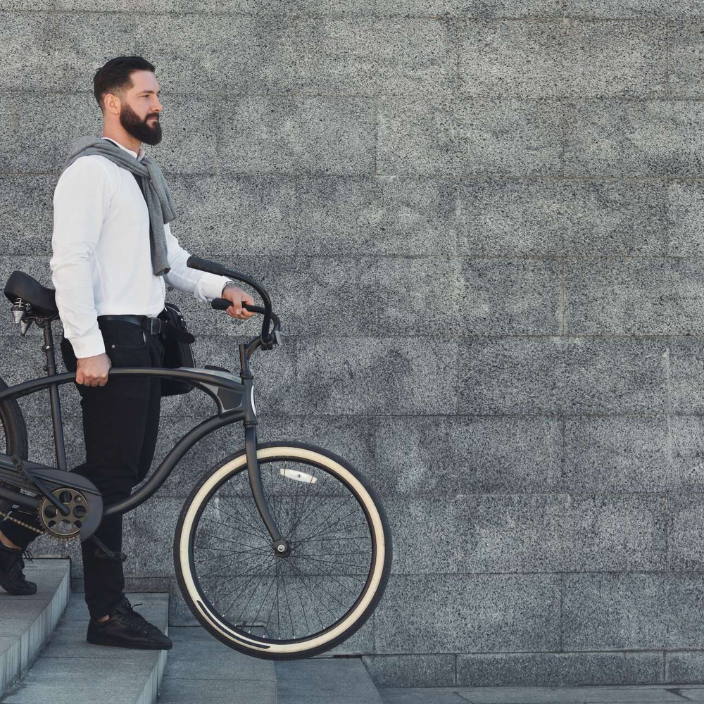 Über das Gewicht von Fahrrädern Ein Mann hält in seiner linken Hand sein Fahrrad fest.