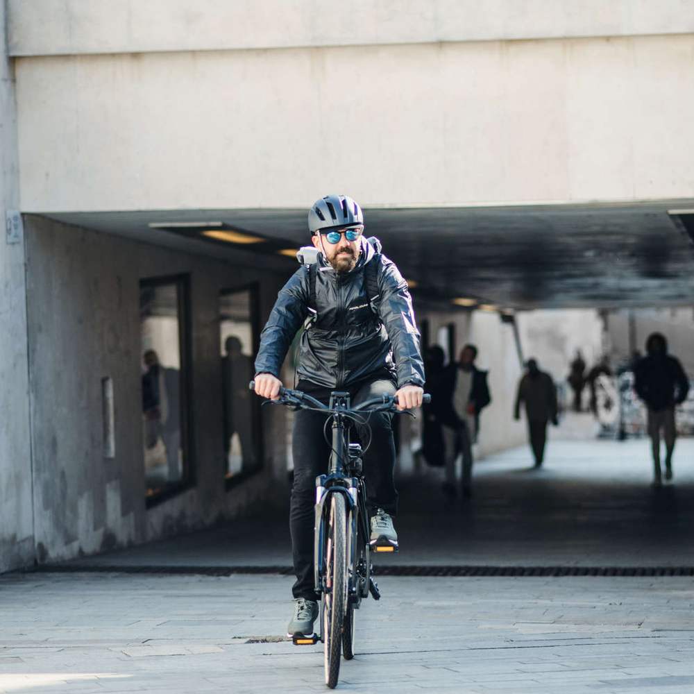 Das Urtopia Chord X: E-Bike mit Sprachsteuerung. Mann mit Helm fährt mit E-Bike durch Stadt.