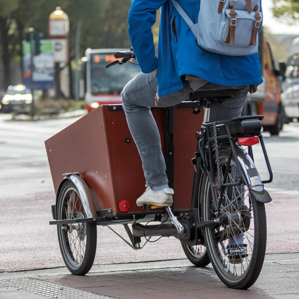 Person fährt auf einem Lastenfahrrad entlang einer Stadtstraße
