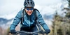 Radfahren im Winter macht Spaß - wenn nicht gerade akute Glatteisgefahr besteht. Frontale Ansicht einer lächelnden Fahrradfahrerin in Winterkleidung
