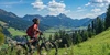 Ist das Light-E-MTB der neue Mega Trend 2024? Frau schiebt E-Mountainbike durch die Berge