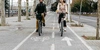 So bist du auf deinem E-Bike sicher unterwegs. Zwei Personen fahren nebeneinander auf Fahrrädern über einen Radweg.