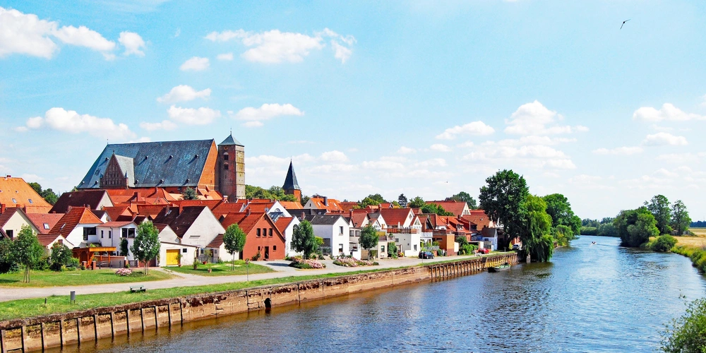 Panorama einer Stadt mit Häusern und einem Fluss unter blauem Himmel.