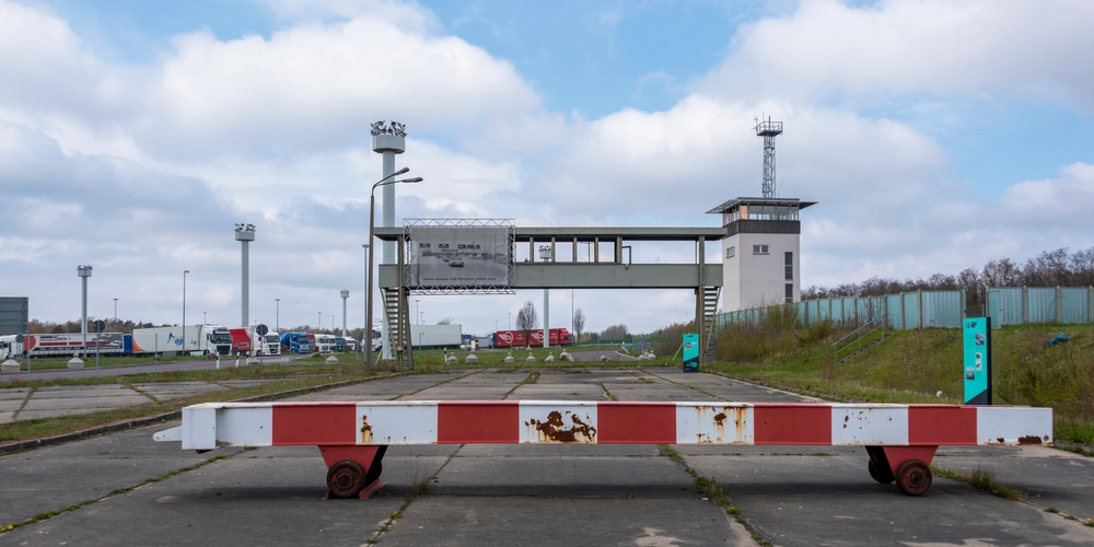 Gesperrte Zufahrt mit einer weißen und roten Schranke vor einem Kontrollzentrum.