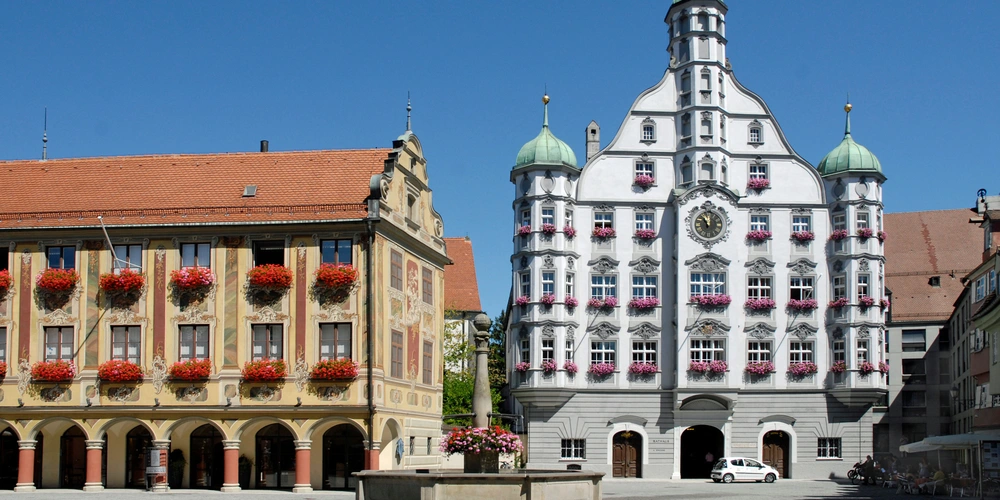 Zwei historische Gebäude mit farbenfrohen Fassaden unter klarem, blauem Himmel.