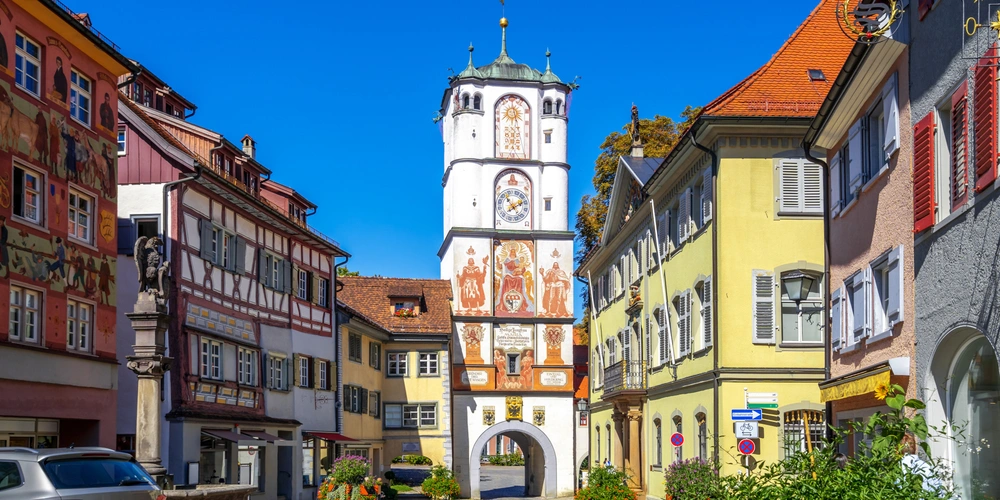 Farbenfrohe Gebäude und ein historischer Turm in einer sonnigen Straße.