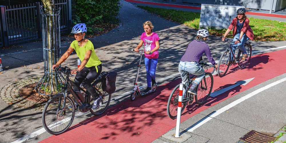 Mehrere Fahrradfahrer auf einem Fahrradweg an einem sonnigen Tag.