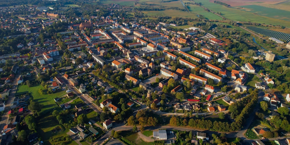 Luftaufnahme einer Stadt mit Häusern, Straßen und Grünflächen.