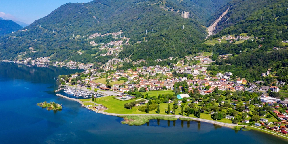 Blick auf eine malerische Stadt am See, umgeben von grünen Bergen.