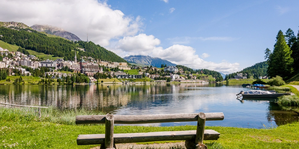 Bank steht am Seeufer mit Blick auf den Olympiaort St. Moritz