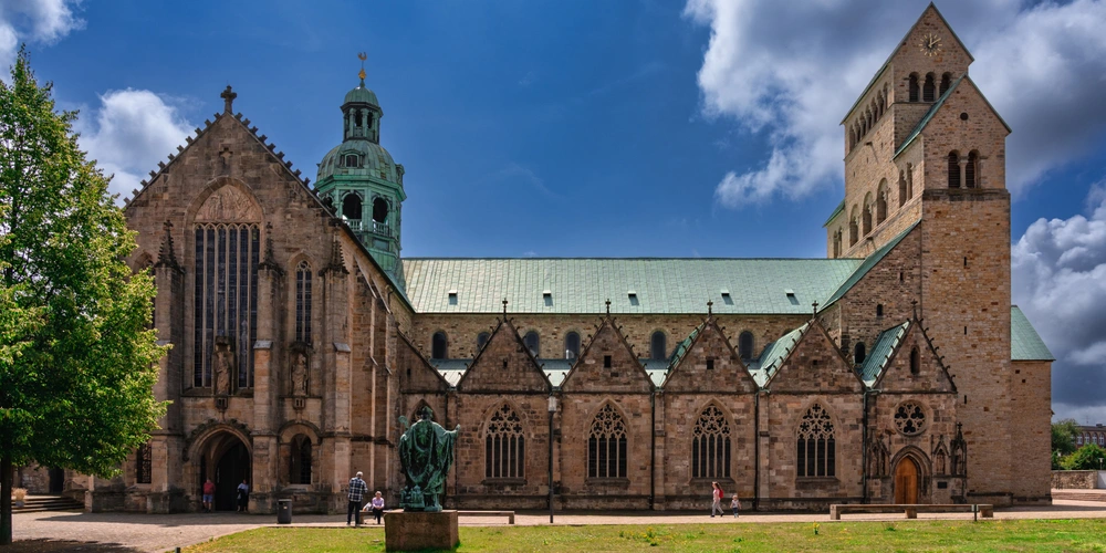 Blick auf eine große, historische Kirche mit grüner Dachturm und hellen Steinmauern.