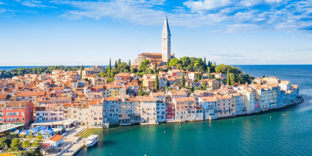 Luftaufnahme der Küstenstadt Rovinj mit bunten Häusern und einem Kirchturm.