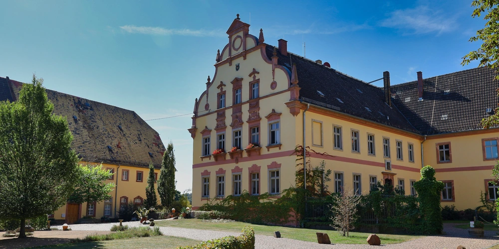 Historisches Gebäude mit gelber Fassade und verzierter Architektur unter blauem Himmel.