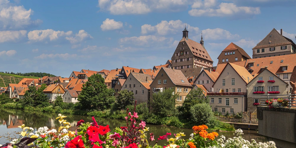 Besigheim an der Neckar Idyllisches Dorf mit traditionellen Häusern, bunten Blumen und Wolken am Himmel.