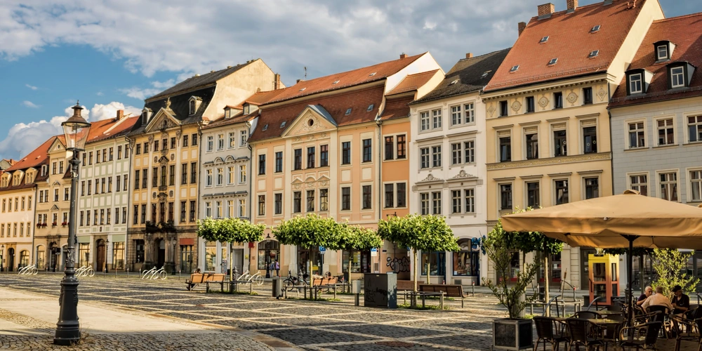 Bunte historische Gebäude entlang einer belebten Straße mit Außenterrassen.