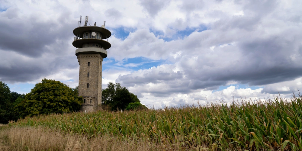 Ein Aussichtsturm steht neben einem Maisfeld unter einem bewölkten Himmel.