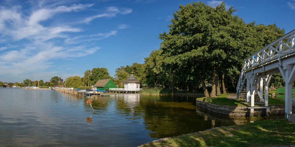 Panoramablick auf einen ruhigen See mit Häusern und Bäumen am Ufer.