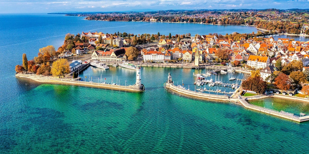 Blick auf Hafen Lindau am Wasser mit herbstlichen Bäumen.