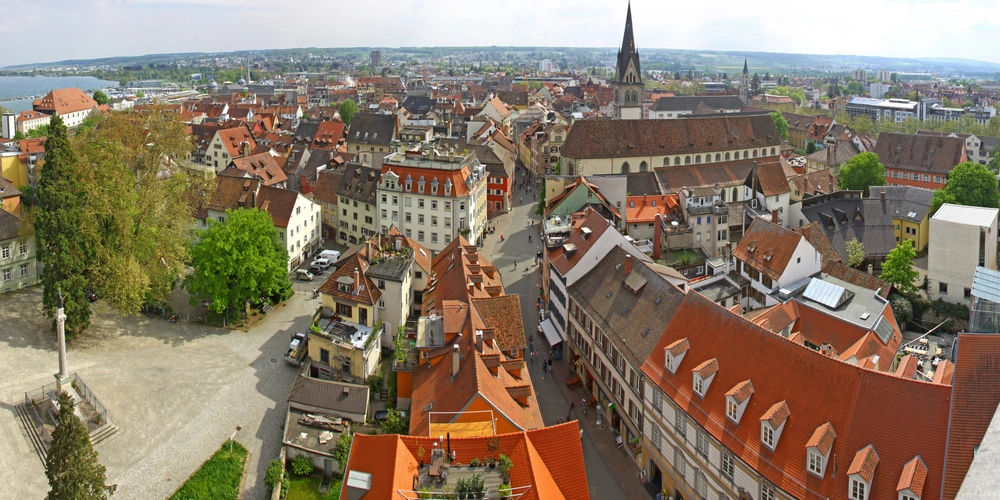 Blick auf eine historische Stadt mit roten Dächern und einer grünen Umgebung.