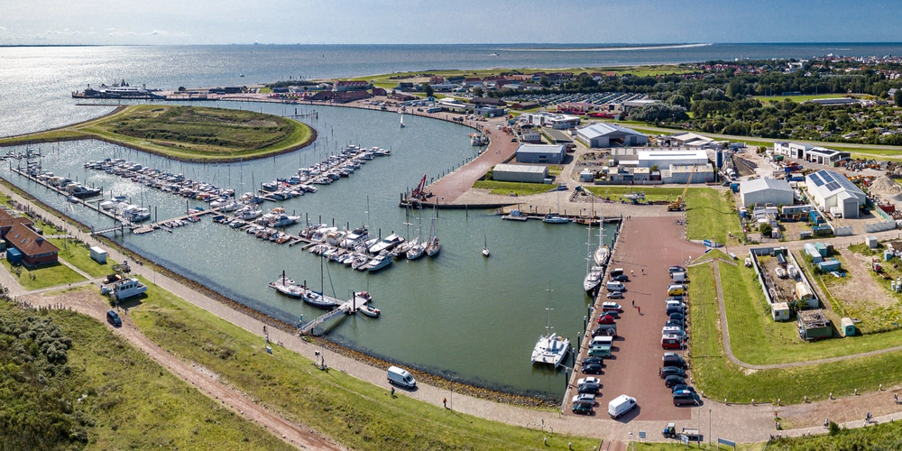 Luftaufnahme eines Yachthafens mit Booten und umgebendem Landschaftsbereich.