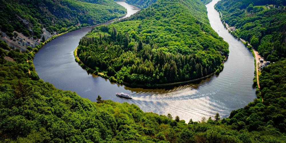 Aussicht auf einen geschwungenen Fluss durch grüne Hügel und Wälder.