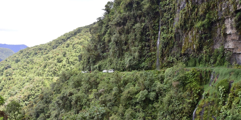 Grüne, steile Hänge mit einer schmalen Straße, die sich am Berg entlang schlängelt.