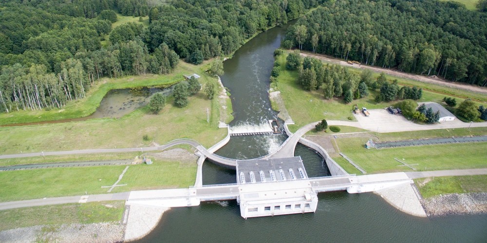 Luftaufnahme eines Kanals mit einer Schleuse und umgebender Natur.