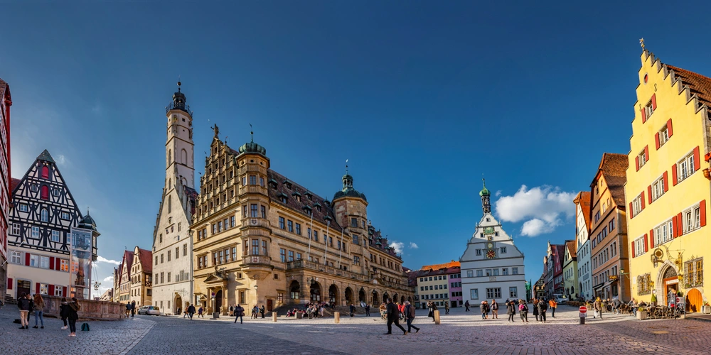 Blick auf den historischen Stadtplatz mit bunten Gebäuden und einem klaren blauen Himmel.