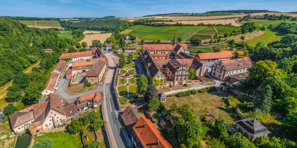 Luftaufnahme eines malerischen Dorfes umgeben von Hügeln und Feldern.