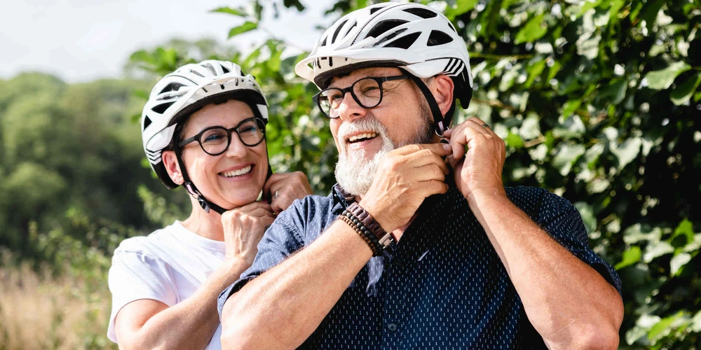 Zwei Personen schließen ihre Fahrradhelme und bereiten sich auf eine Fahrt vor