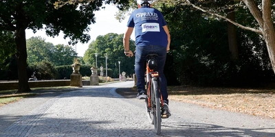 Christian Prokop auf einem Kiesweg, umgeben von Bäumen, an einem sonnigen Tag.