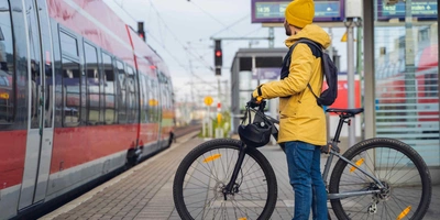 Mann in gelber Jacke wartet mit seinem Fahrrad auf den Zug