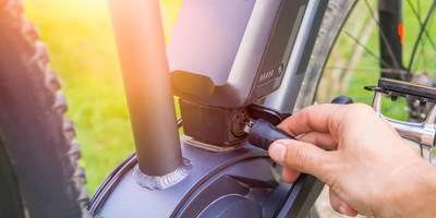 E-Bike Akku 750 Wh – das ist zu beachten Person verbindet ein Kabel mit dem Akku 750 h eines E-Bikes, um diesen zu laden