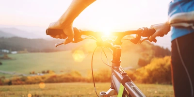 Der 4-Seen-Radweg - wie du deine Tour am besten gestaltest Ein Mann steht mit dem Fahrrad dem Sonnenuntergang entgegen