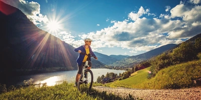 Eine Frau fährt mit dem Fahrrad vor einem See entlang