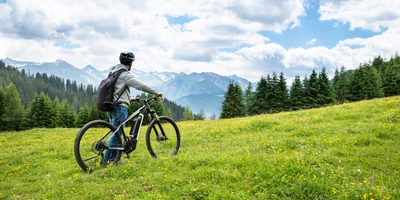 Welche E-Bike Tour sich für deine Familie eignet Ein Mann steht mit seinem E-Bike auf einem Berg