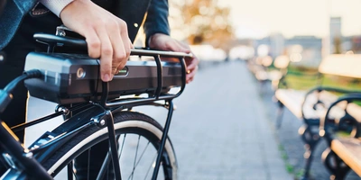 Was sie beim E-Bike fahren ohne Akku beachten sollten Nahaufnahme wie ein Mann seinen E-Bike Akku bedient