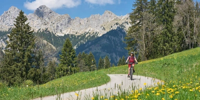 Frau fährt mit einem Fahrrad durch bergige Natur.