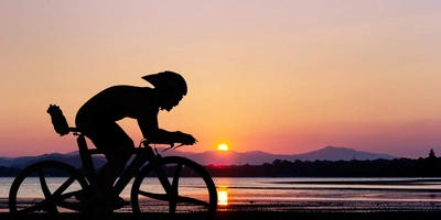 Fahrradfahrer fährt im Dunkeln am Wasser entlang