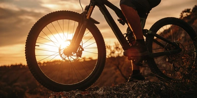Mann fährt mit einem Fahrrad über einen Felden im Sonnenuntergang