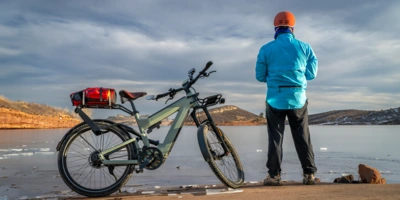 Mann steht mit E-Bike an einem See