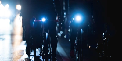Eine Gruppe Fahrradfahrer fährt bei Nacht Fahrrad in der Stadt und haben Lichter an.