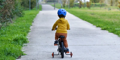 Kind fährt auf einem Fahrrad mit Stützrädern