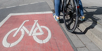 Radfahrer steht auf einem roten Fahrradweg mit einem weißen Fahrradsymbol