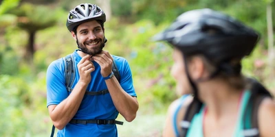 Der richtige Fahrradhelm kann Leben retten. Mann setzt Fahrradhelm auf und schaut Frau an.