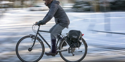 Mann fährt im Winter mit Fahrrad über verschneiten Radweg