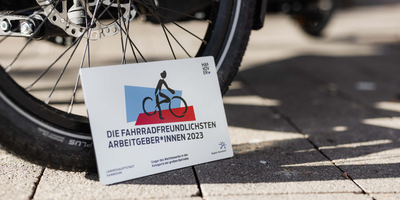 Die Wertgarantie Group ist der fahrradfreundlichste Arbeitgeber 2023. Schild mit Aufschrift "Fahrradfreundlichster Arbeitgeber" steht vor Fahrrad