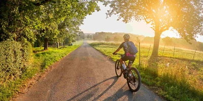 Mountainbikerin fährt durch Feld bei Sonnenuntergang